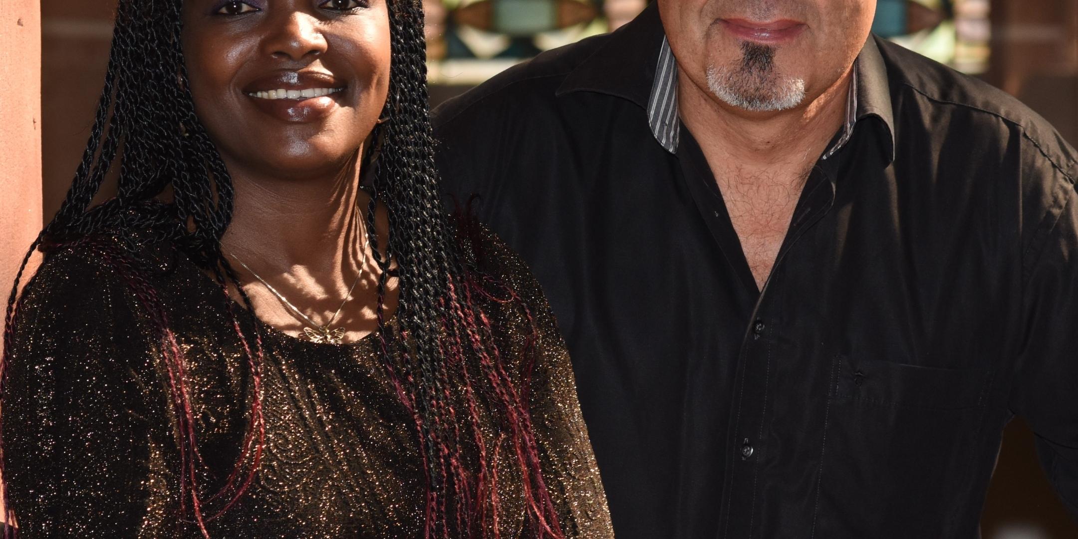 Efe May und Stefan Schömer stehen vor einem bunten Kirchenfenster